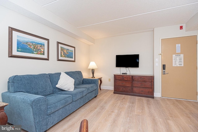 living area with light wood-type flooring, baseboards, and a textured ceiling