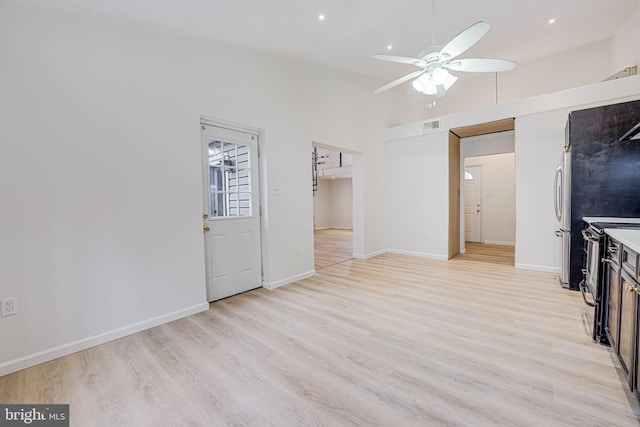 interior space featuring light wood finished floors, visible vents, a ceiling fan, high vaulted ceiling, and baseboards