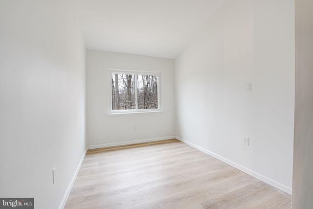 spare room featuring baseboards and light wood finished floors