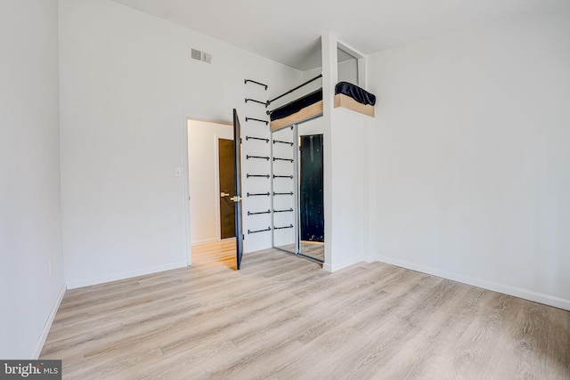 empty room featuring light wood-type flooring, visible vents, and baseboards