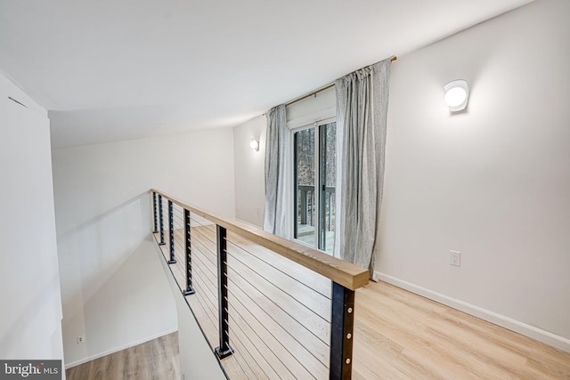 hall with baseboards, an upstairs landing, and wood finished floors