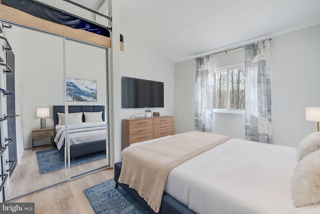 bedroom featuring light wood-type flooring, a closet, and lofted ceiling