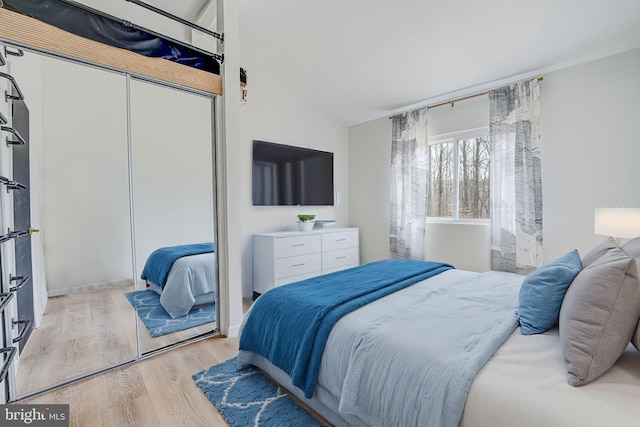 bedroom with lofted ceiling, a closet, and light wood-style floors