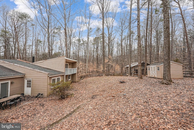 view of yard featuring a storage shed, an outdoor structure, and a balcony