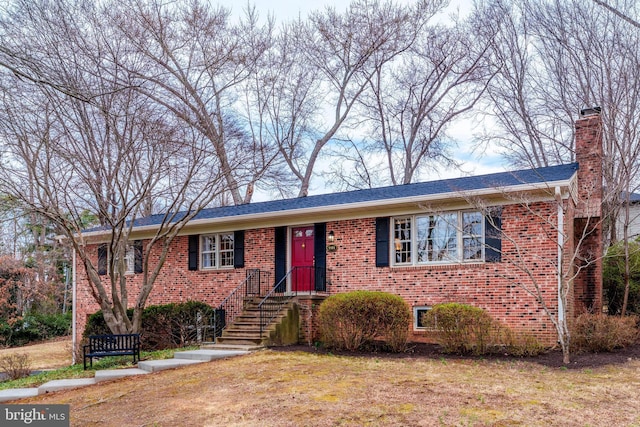 ranch-style home with a chimney, a front lawn, and brick siding