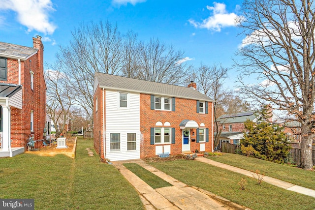 view of front of home with a front lawn, a chimney, and brick siding