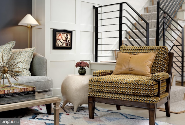 sitting room with stairway, wood finished floors, and a decorative wall