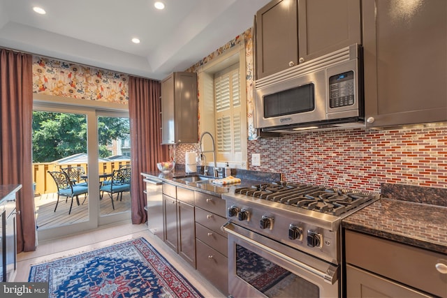 kitchen with dark stone counters, recessed lighting, a sink, appliances with stainless steel finishes, and tasteful backsplash