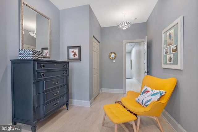 sitting room with a notable chandelier, light wood-type flooring, and baseboards