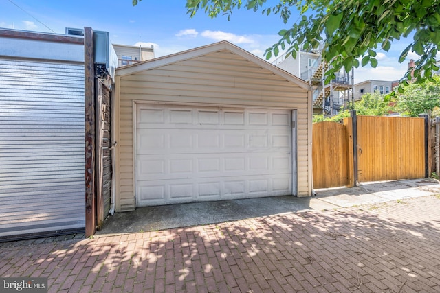 garage featuring decorative driveway, a gate, and fence