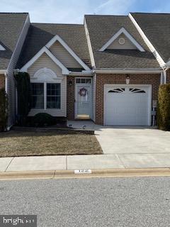 view of front facade with a garage, brick siding, and driveway