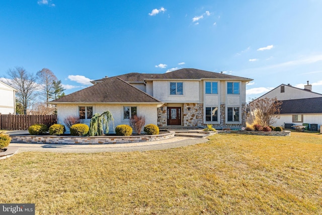 traditional home with stone siding, fence, a front lawn, and stucco siding