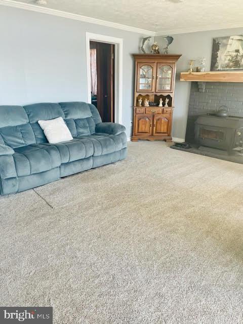 living room featuring ornamental molding, light colored carpet, a fireplace, and a textured ceiling