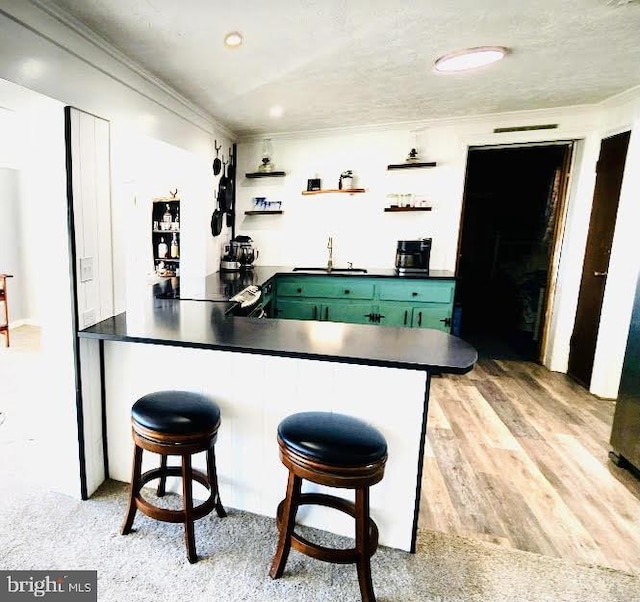 bar with ornamental molding, light wood-type flooring, and a sink