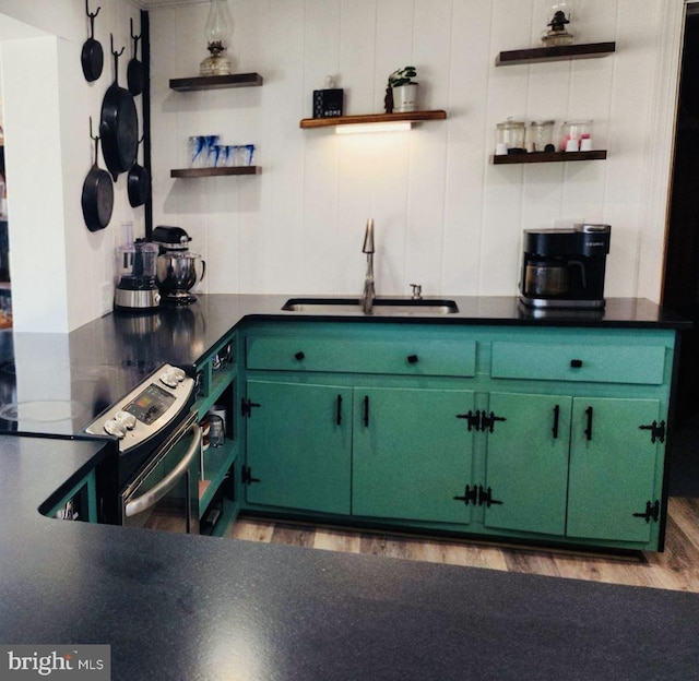 kitchen with light wood-style flooring, a sink, stainless steel electric range oven, open shelves, and dark countertops