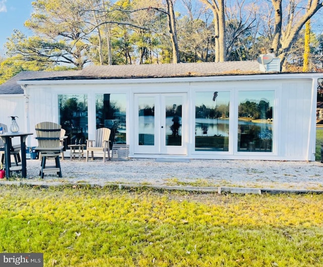 back of property with a chimney and a lawn