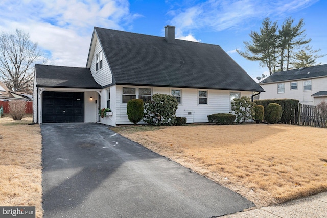 view of front facade with aphalt driveway, a chimney, an attached garage, fence, and a front lawn