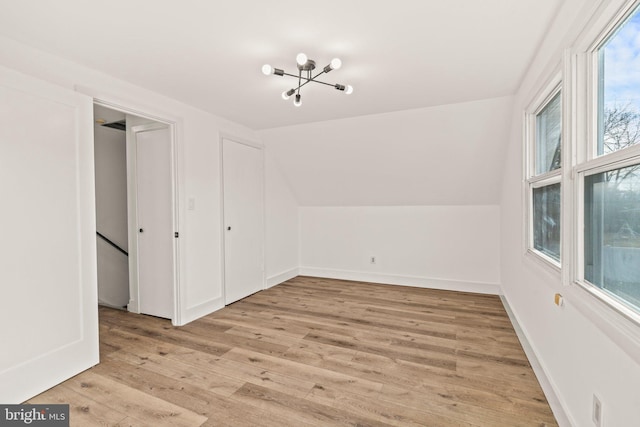 additional living space with vaulted ceiling, light wood-style flooring, and baseboards