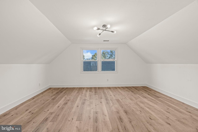 additional living space featuring light wood-style floors, baseboards, and vaulted ceiling