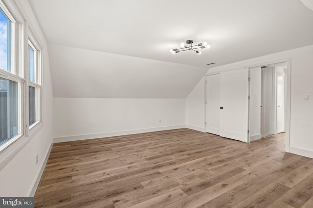 additional living space featuring vaulted ceiling, baseboards, and wood finished floors