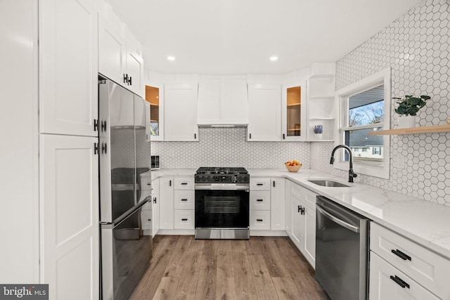 kitchen with appliances with stainless steel finishes, white cabinetry, a sink, and open shelves