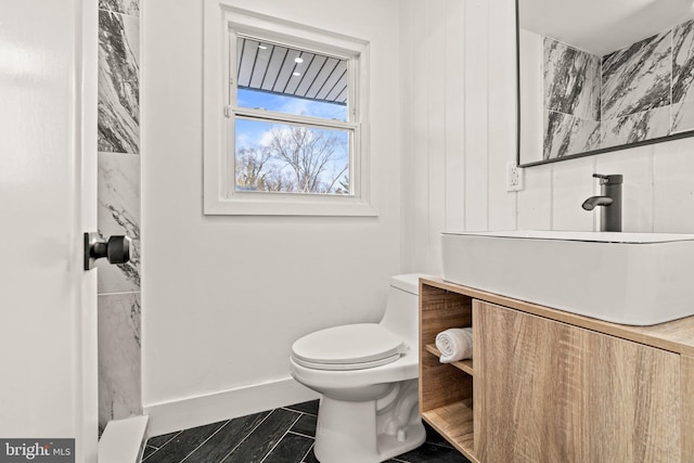 bathroom with toilet, baseboards, and vanity