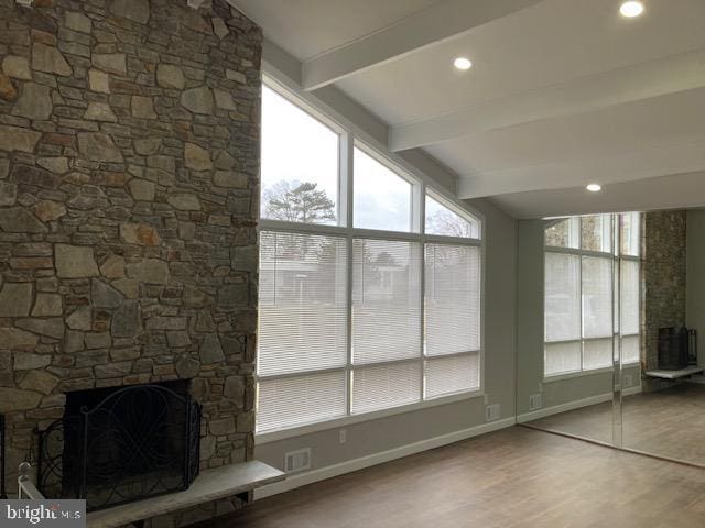 unfurnished sunroom with a fireplace and lofted ceiling with beams