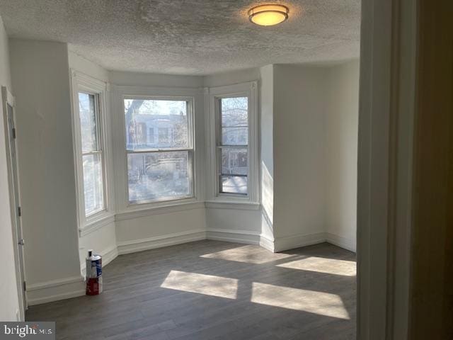 interior space with dark wood-style floors, a textured ceiling, and baseboards