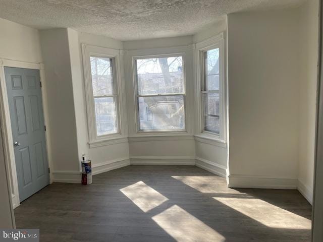 unfurnished dining area with dark wood-style floors, baseboards, and a textured ceiling