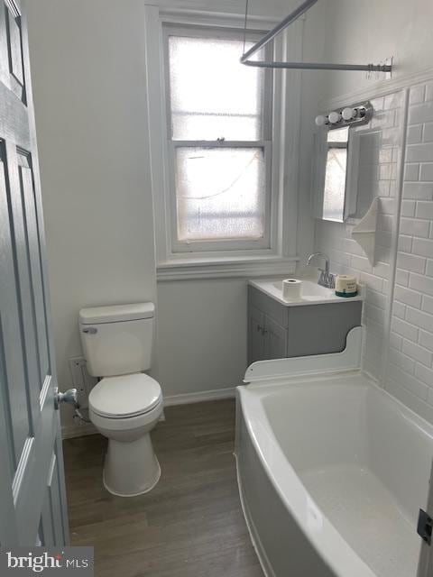 full bathroom featuring toilet, wood finished floors, vanity, and baseboards