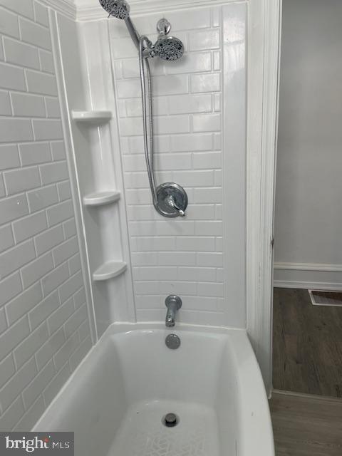 full bathroom featuring visible vents, wood finished floors, shower / tub combination, and baseboards