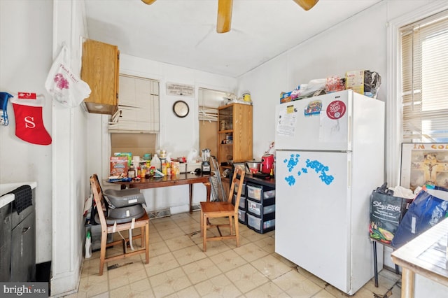 kitchen featuring light floors, ceiling fan, and freestanding refrigerator