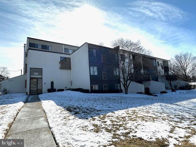 snow covered property featuring stucco siding