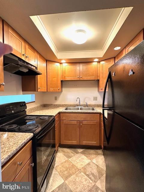 kitchen featuring black appliances, under cabinet range hood, a raised ceiling, and a sink