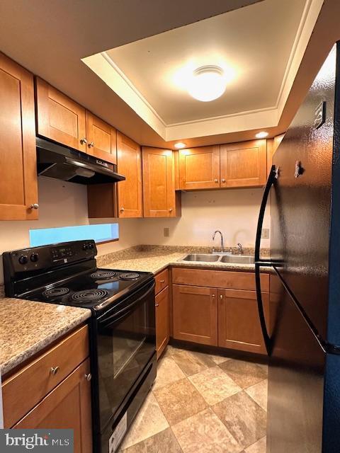 kitchen with black appliances, under cabinet range hood, a tray ceiling, and light countertops