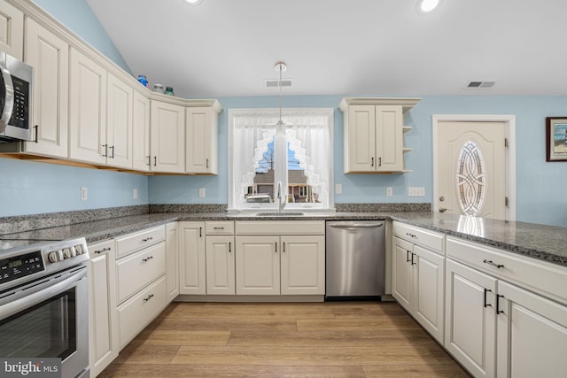 kitchen with stainless steel appliances, visible vents, light wood-style floors, and a sink