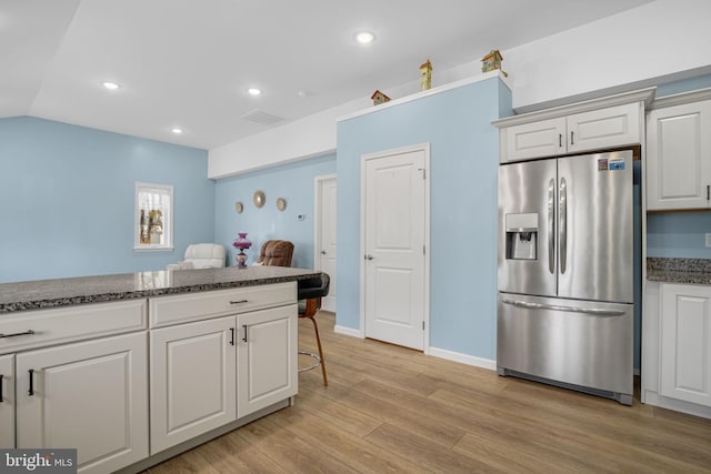 kitchen featuring light wood-type flooring, stainless steel fridge, a kitchen breakfast bar, and recessed lighting