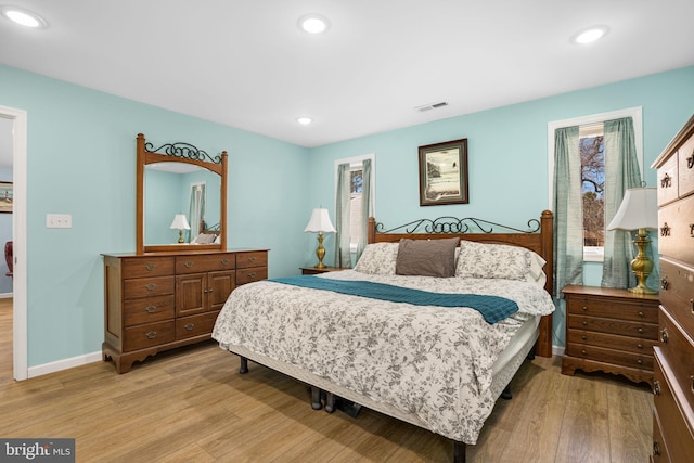 bedroom with baseboards, light wood-style flooring, visible vents, and recessed lighting