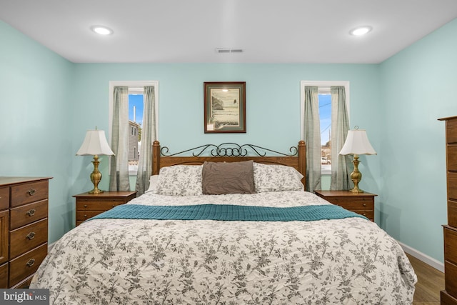 bedroom with recessed lighting, wood finished floors, visible vents, and baseboards