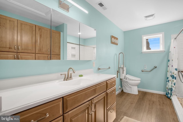 bathroom featuring baseboards, visible vents, toilet, wood finished floors, and vanity