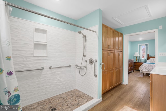 ensuite bathroom featuring tiled shower, wood finished floors, and connected bathroom