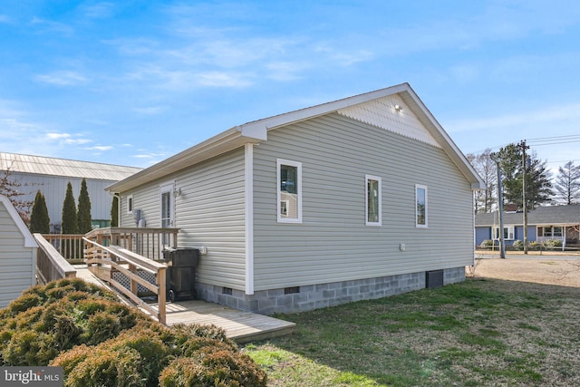 view of side of home with crawl space, a lawn, and a wooden deck