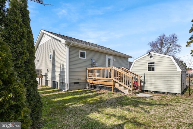 rear view of property featuring an outbuilding, a storage shed, a shingled roof, a lawn, and a wooden deck