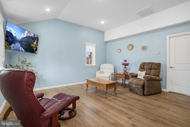 sitting room with lofted ceiling, visible vents, baseboards, and wood finished floors