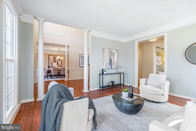 living room featuring ornamental molding, an inviting chandelier, wood finished floors, and ornate columns