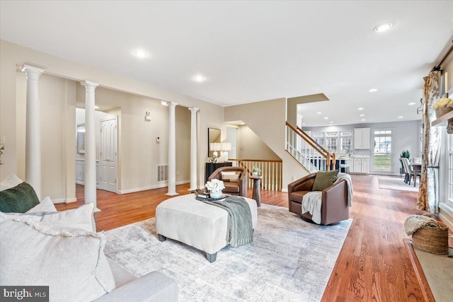 living area featuring visible vents, stairway, wood finished floors, ornate columns, and recessed lighting