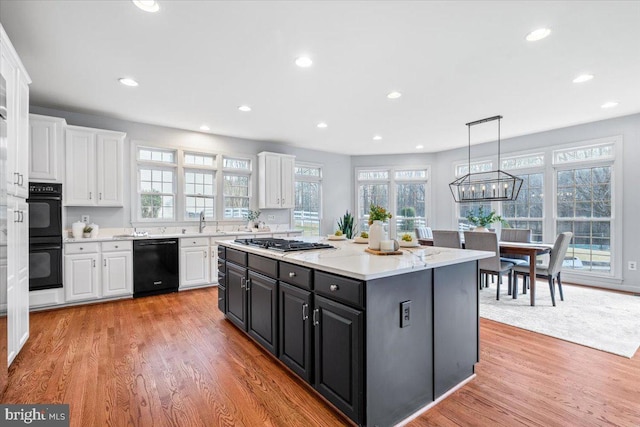 kitchen featuring white cabinetry, light wood finished floors, black appliances, and dark cabinetry