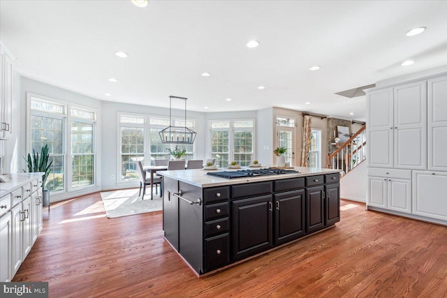 kitchen with wood finished floors, dark cabinetry, gas stovetop, white cabinetry, and recessed lighting