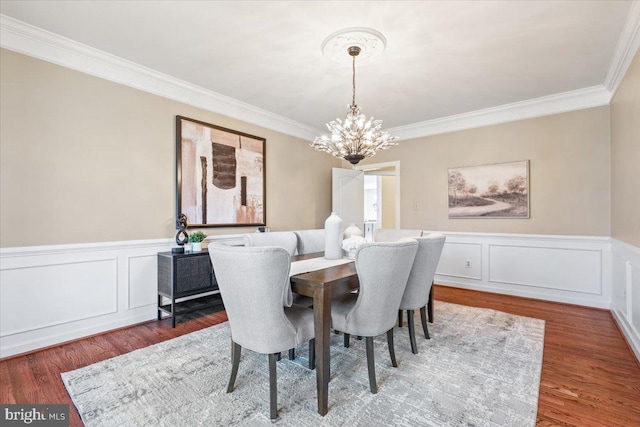 dining space with a chandelier, wainscoting, wood finished floors, and crown molding