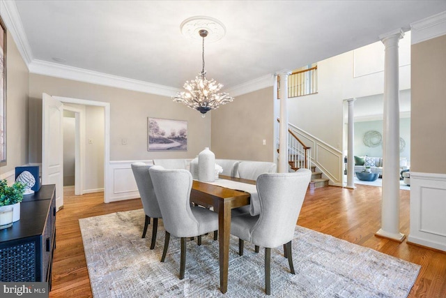 dining room featuring ornamental molding, wood finished floors, decorative columns, and a notable chandelier